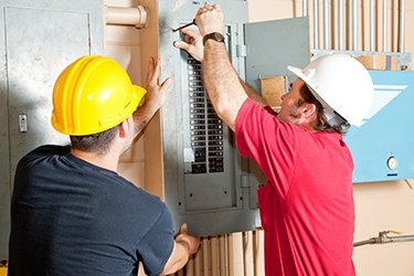 Commercial electricians in Edmonton working on a breaker panel at a business
