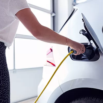 woman charging electric vehicle in her garage at home